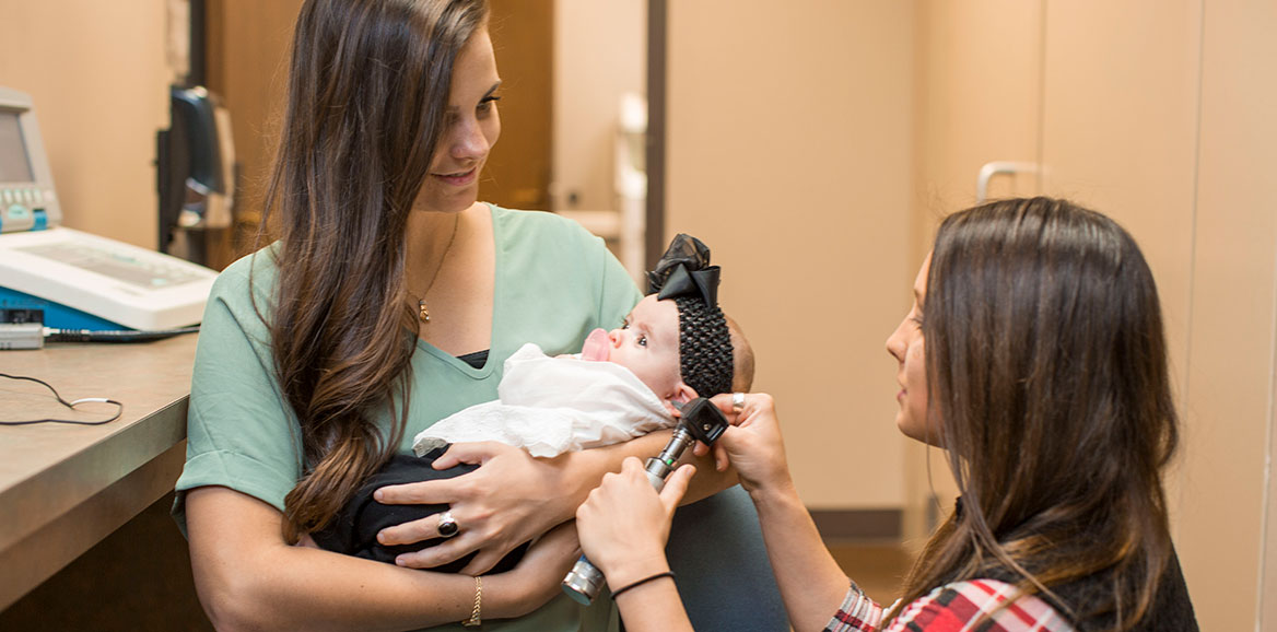 An Audiologist exams an infants ear