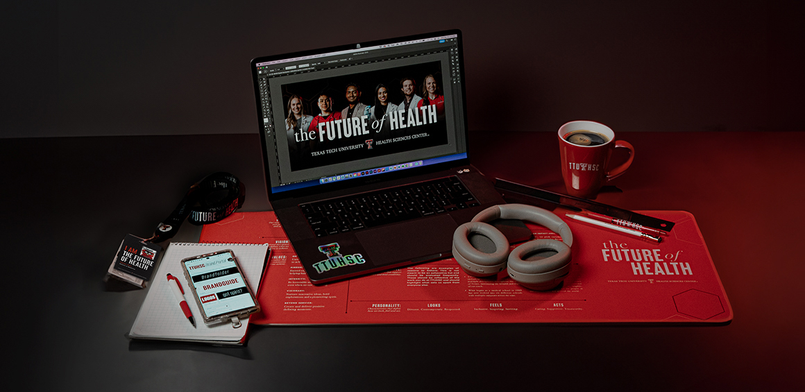 Flat lay image of a laptop and various items branded with The Future of Health artwork. 