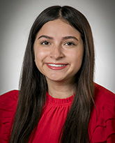 A woman wearing a red shirt with long brown hair smiling. 