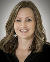 A woman with long brown hair wearing a black shirt smiling.