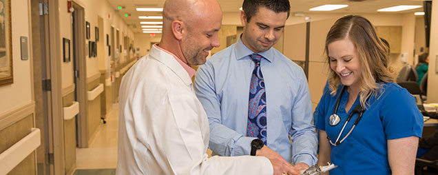 A health care administration professional discusses patient care with a physician and a nurse.