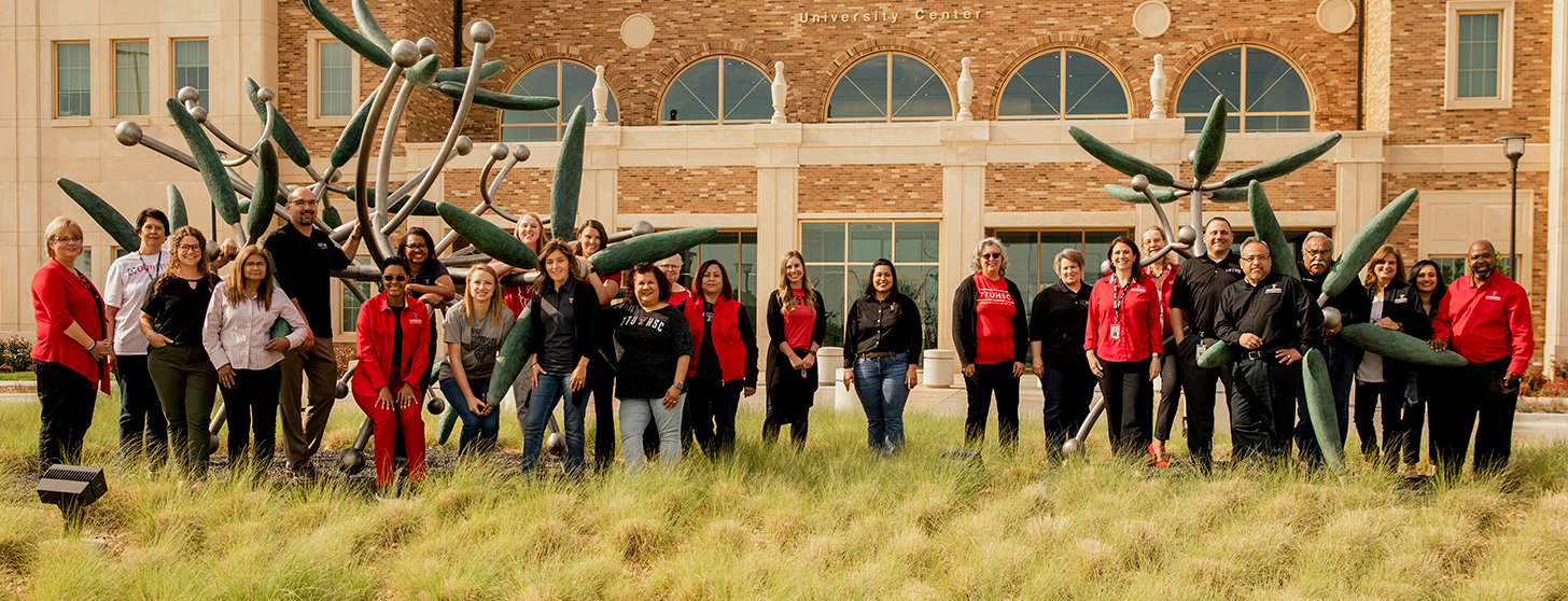 Group photo of TTUHSC Team Members standing in front of the University Center building on the Texas Tech University Health Sciences Center campus in Lubbock