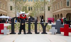 Raider Red posing with the big fifty display at the ribbon cutting for the University Center.