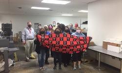 TTUHSC Printing Center staff holding mask for dinosaurs