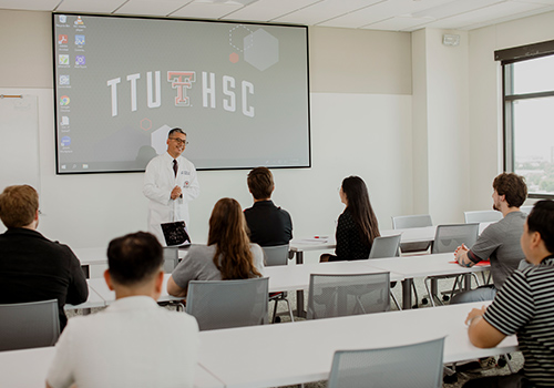 Group of TTUHSC students sitting in a classroom facing the front as an instructor speaks infront of a screen