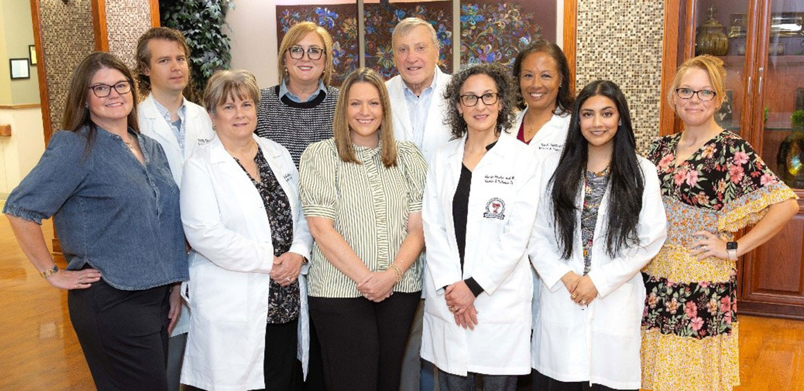 A group photo of nine healthcare professionals and staff members from the Hospice and Palliative Medicine Fellowship standing together indoors.