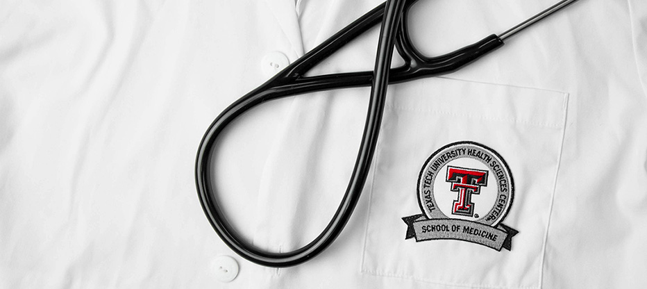 White coat with TTUHSC School of Medicine logo and a stethescope laying on top of the coat