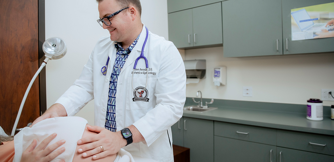 TTUHSC provider placing hands on a patients pregnant stomach checking it while the patient lies on patient table