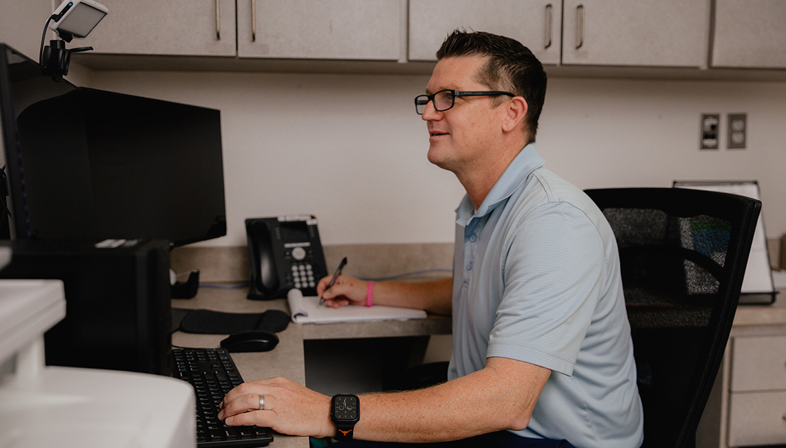 Psychiatry provider sitting at a computer smiling
