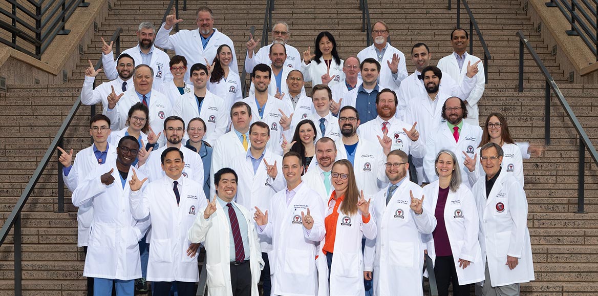 Lubbock Surgical team standing on stairwell with Texas Tech guns up hand motion