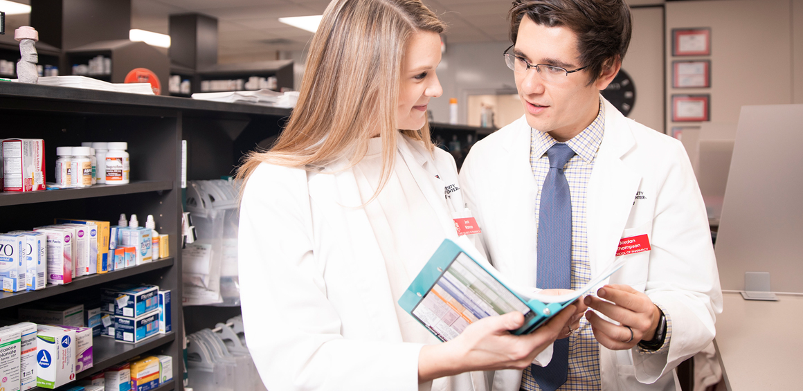 TTUHSC Pharmacy students in the pharmacy looking over a reference book.