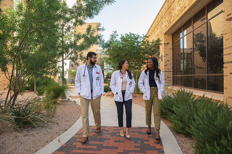 picture of three ttuhsc school of medicine students walking in a courtyard