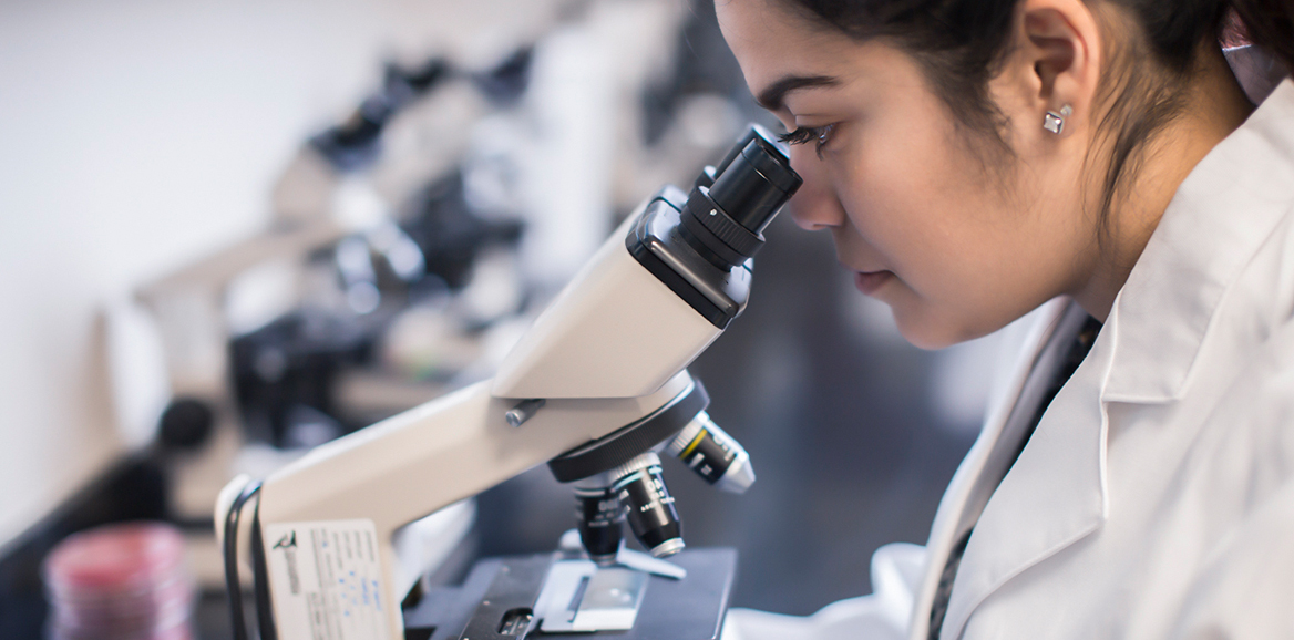 Girl researcher looking through microscope