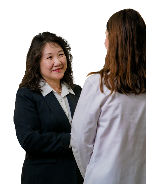 School of Pharmacy Dean Grace Kuo speaks with a student in a white coat.