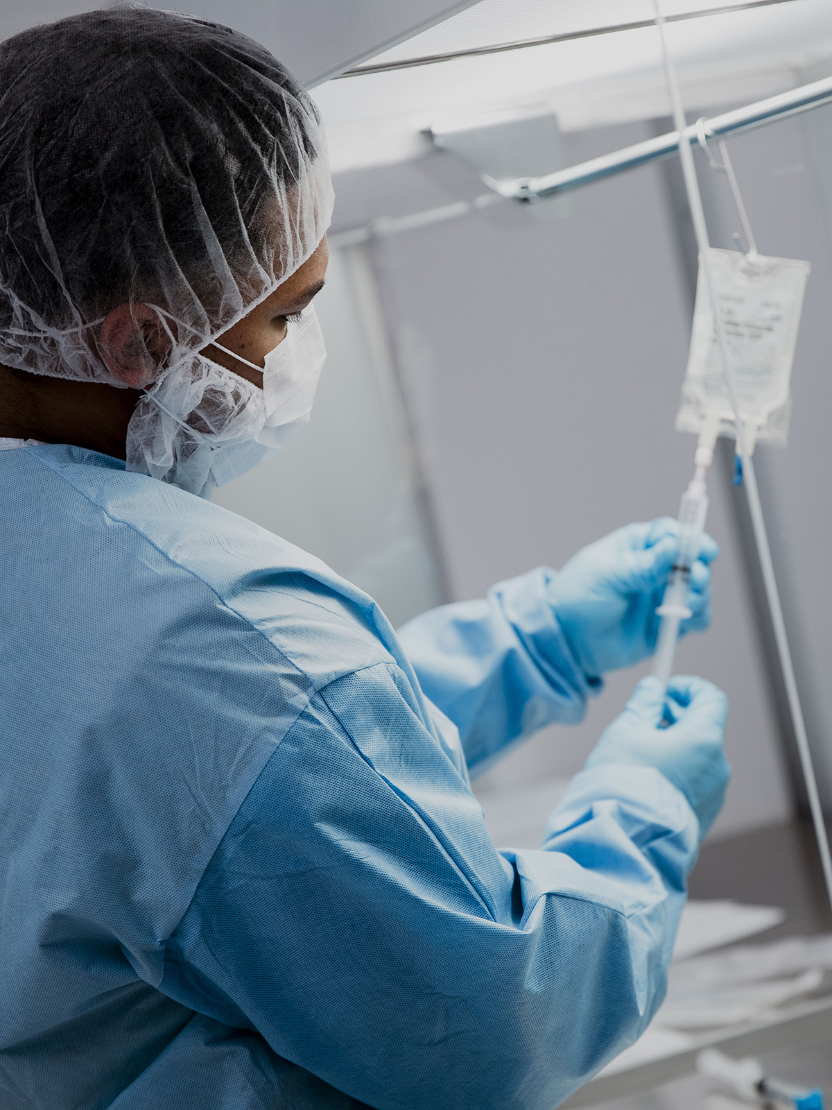TTUHSC Dallas Mansfield pharmacy student in full scrubs administering medication to IV packet.