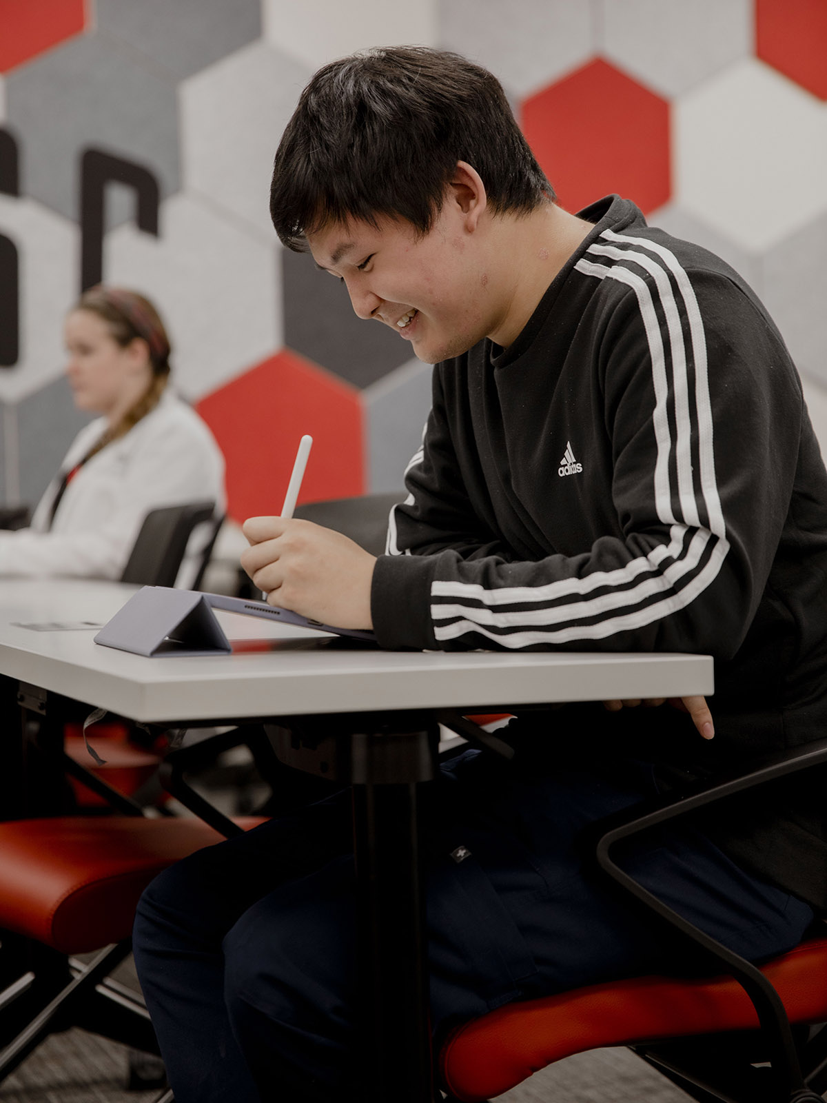 TTUHSC Dallas Mansfield student using a tablet and smart pen sitting in a classroom.