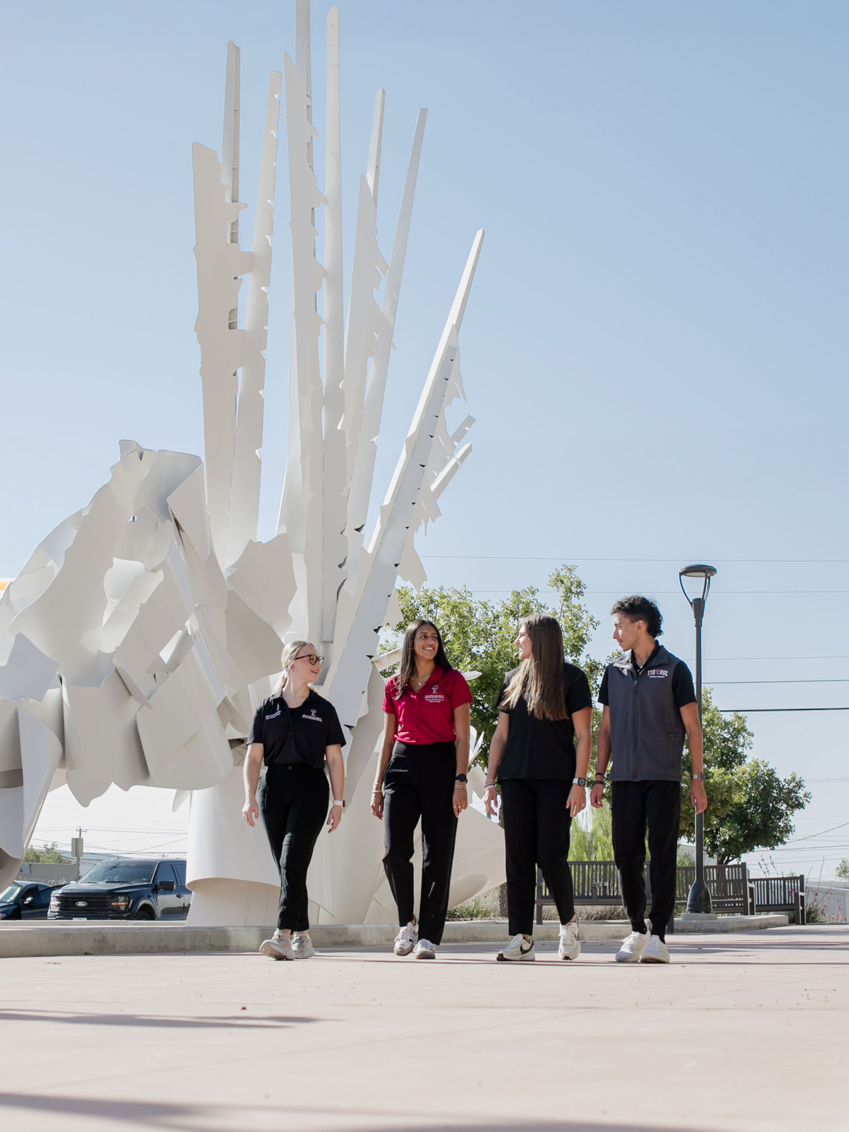 TTUHSC Odessa PT students walking outside with public art sculpture in the background.