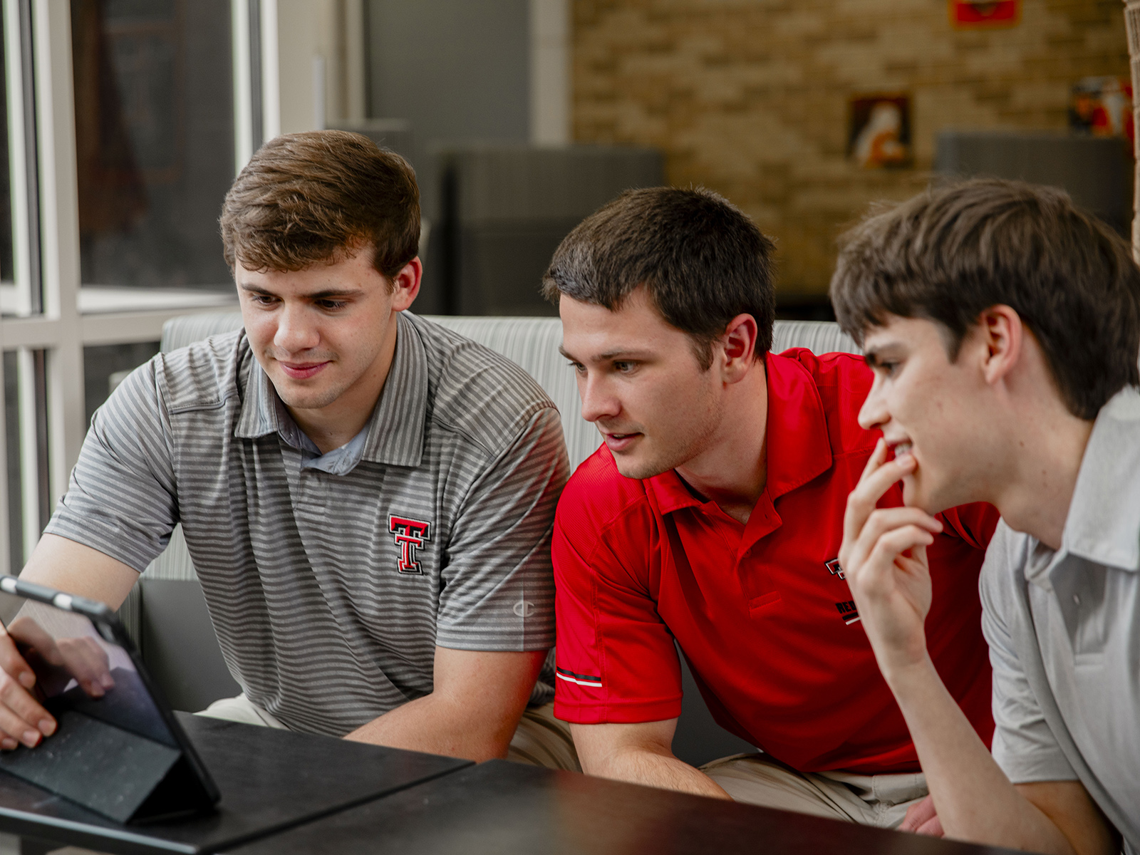 Three students wearing Double T polo shirts looking at one screen at TTUHSC Amarillo