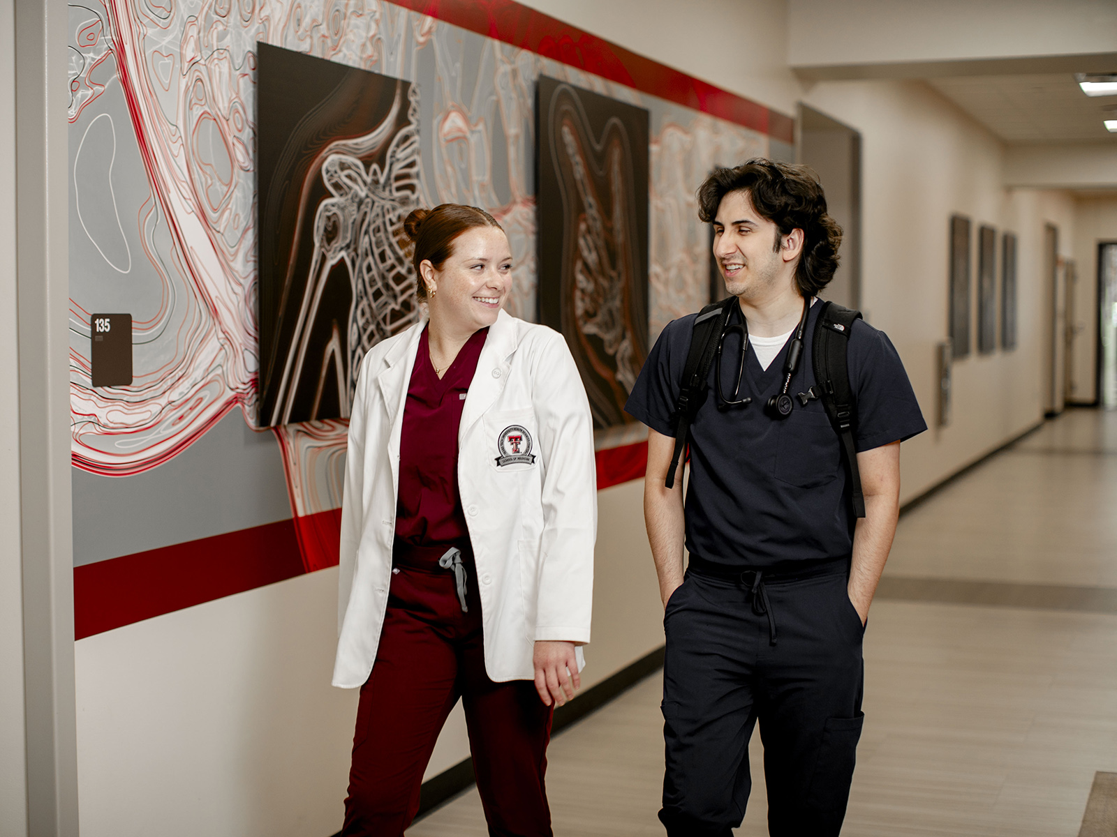 TTUHSC Odessa students walking together in a hallway with body system artwork on the walls