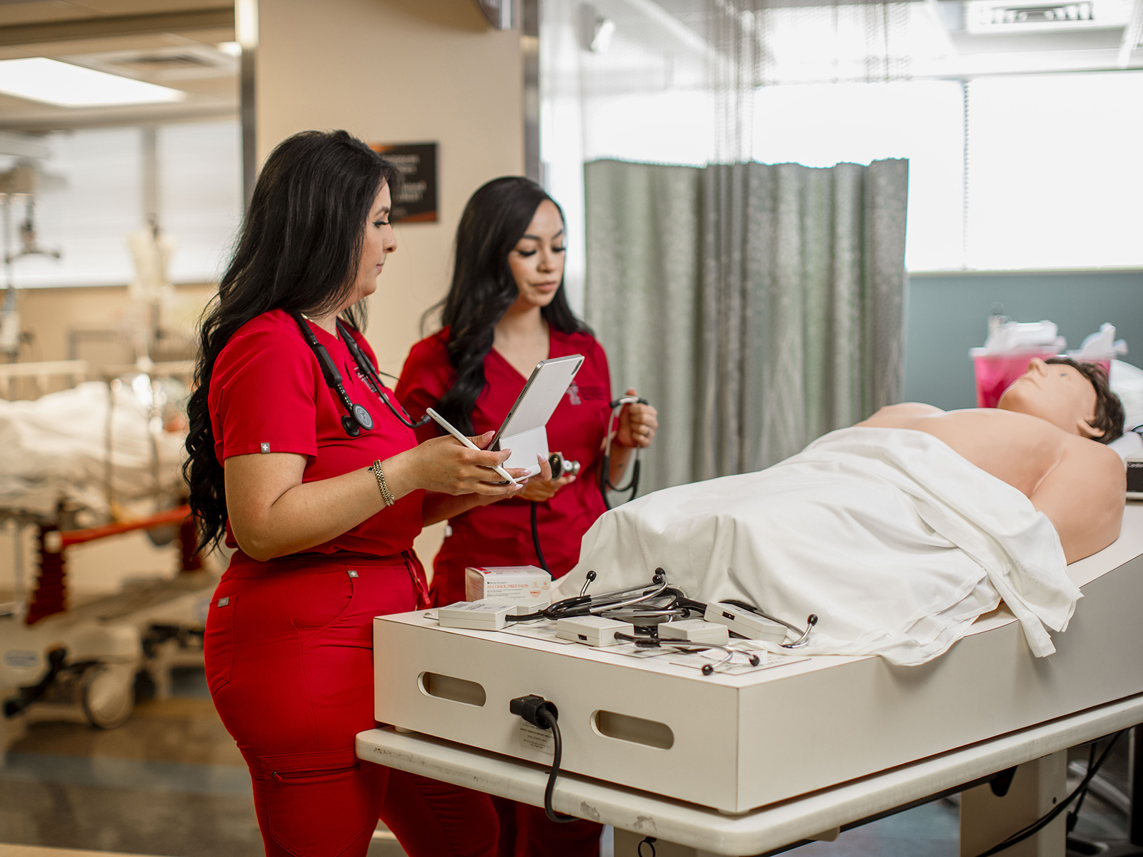 TTUHSC Odessa nursing students with clipboards and simulation mannequin on a bed