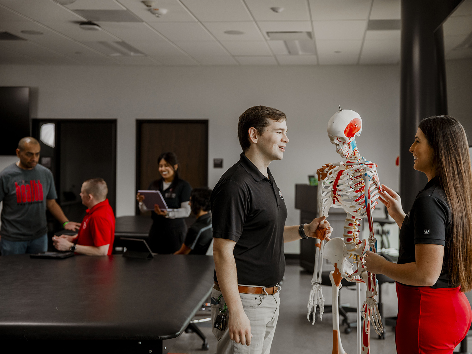 TTUHSC Lubbock School of Health Professions students standing in a classroom looking at a skeleton model