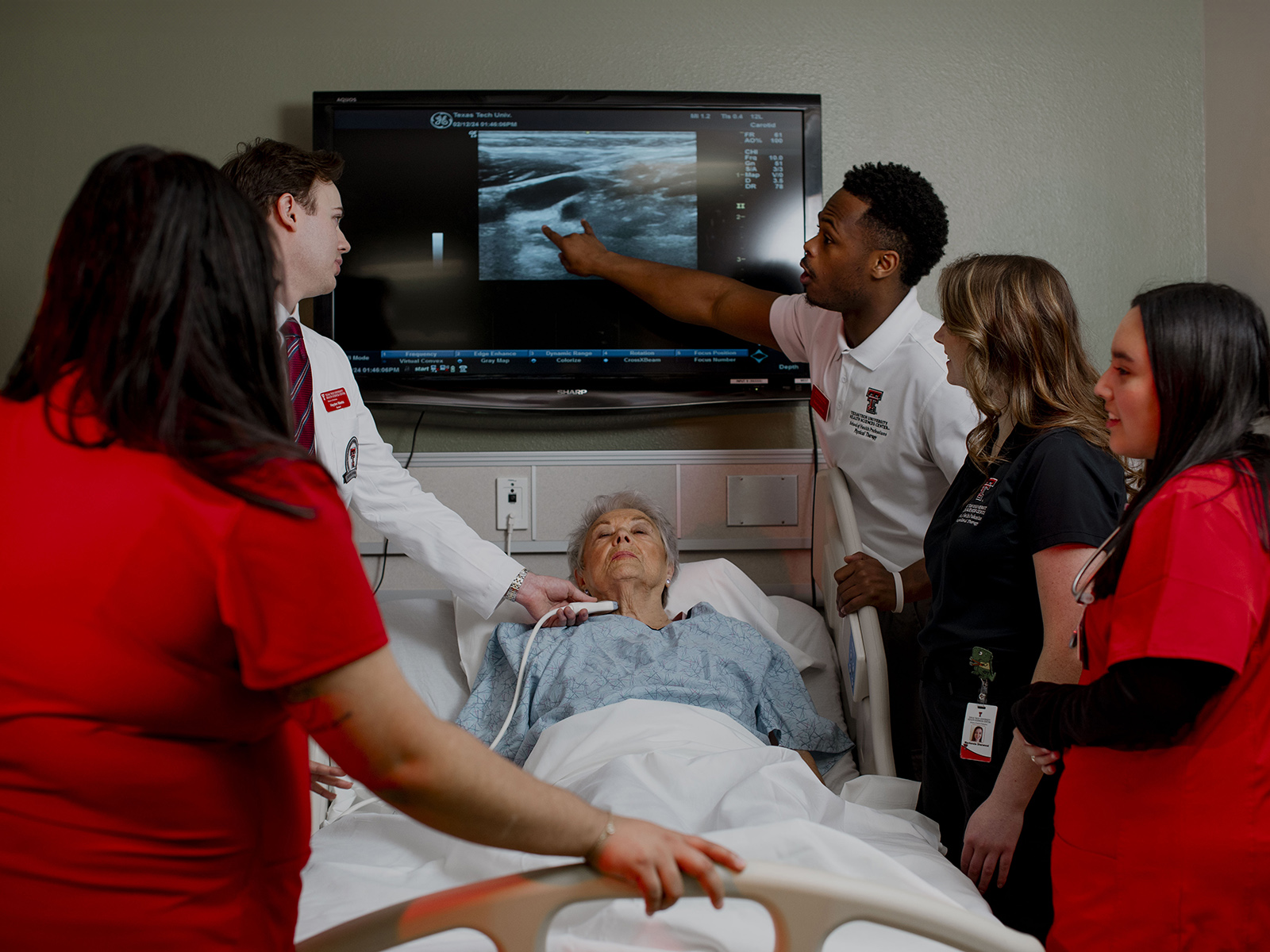 TTUHSC Lubbock students and instructor at a bedside with patient using a sonography machine on a patient looking at a screen