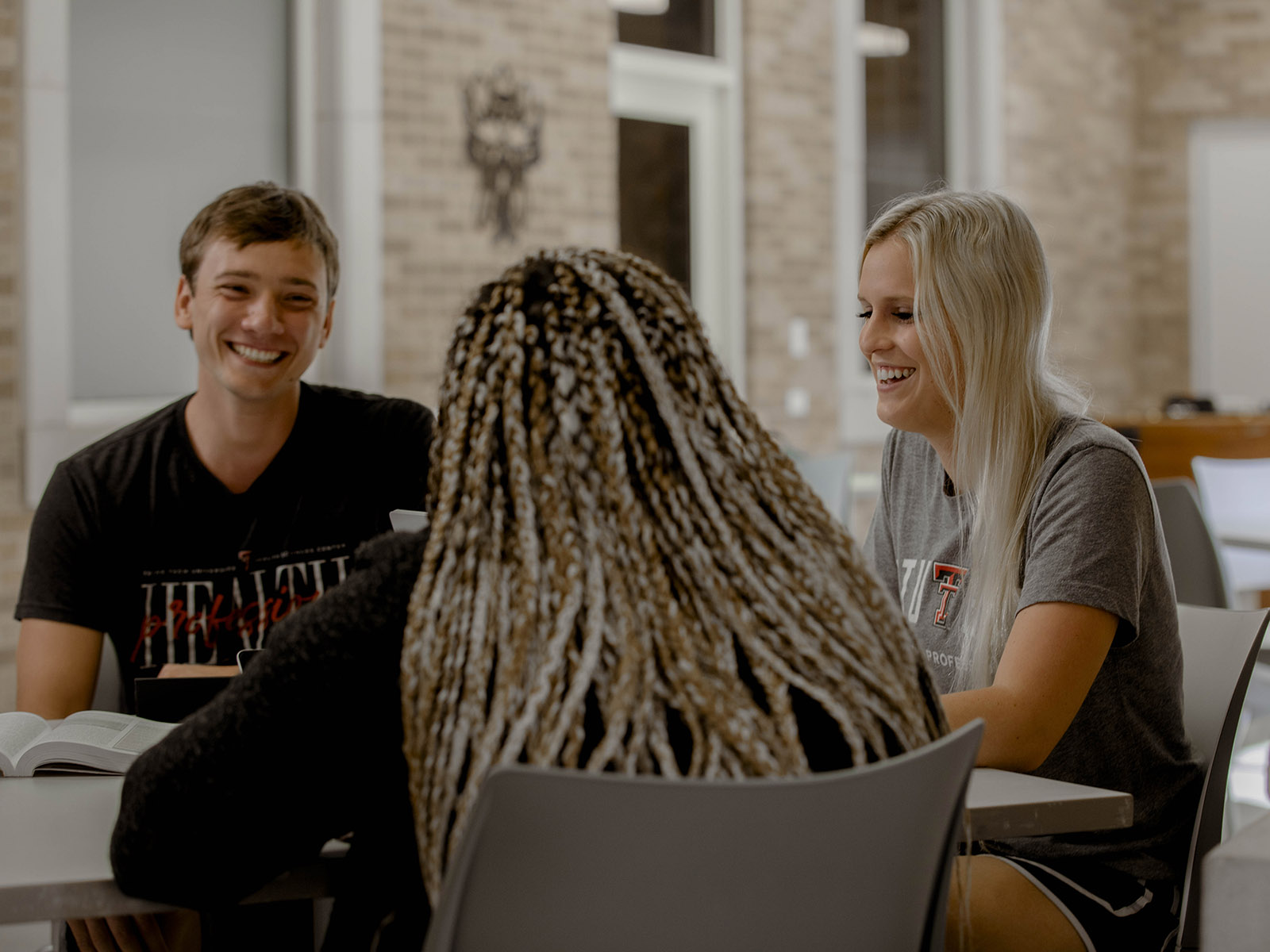 TTUHSC Amarillo students sitting together at a table in the lounge smiling.