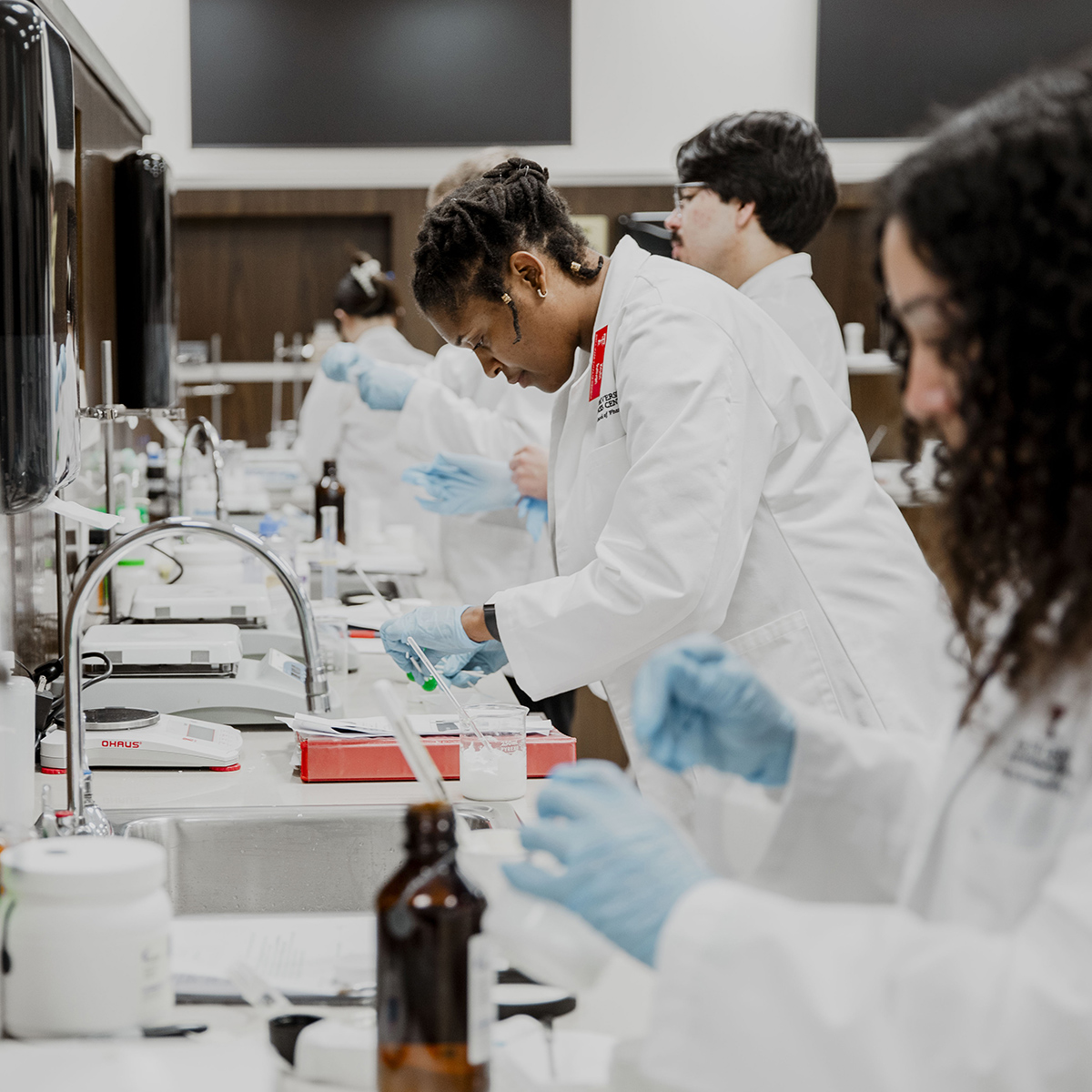 TTUHSC Dallas Mansfield pharmacy students in a laboratory mixing contents.