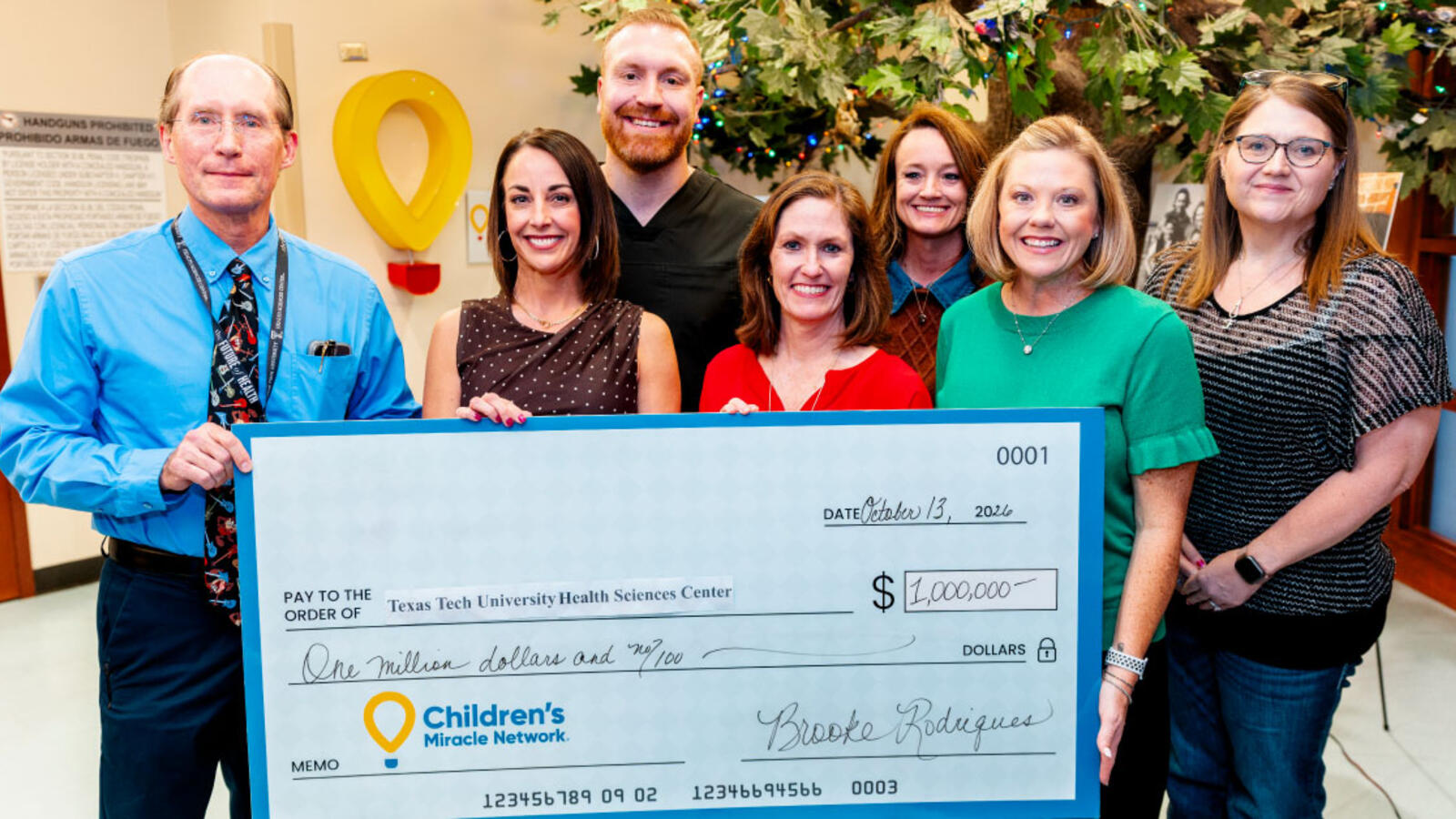 Several people stand in the Texas Tech Physicians Pediatrics waiting room in Amarillo while holding an oversized presentation check.