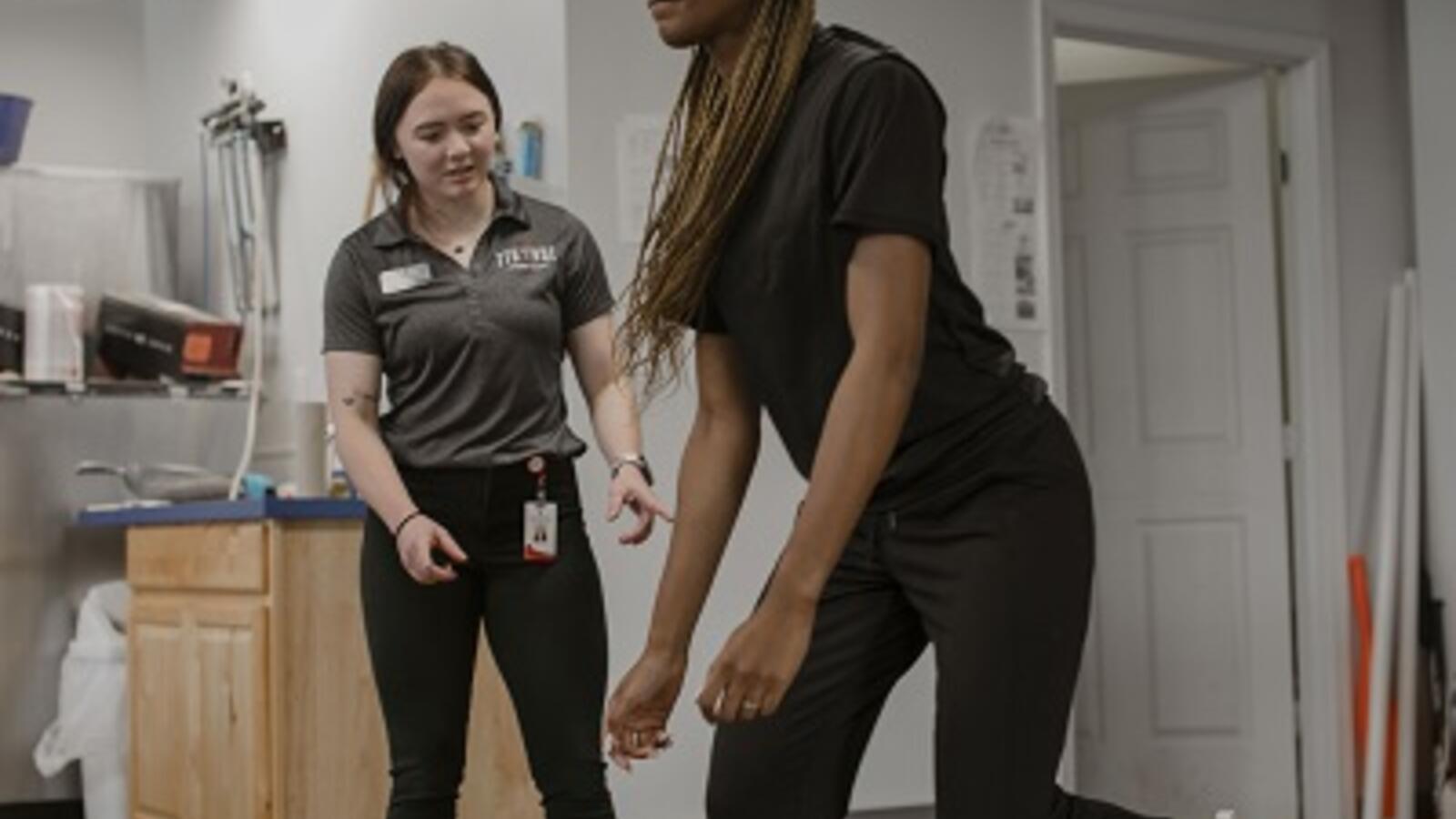 athletic trainer helping an athlete with exercises
