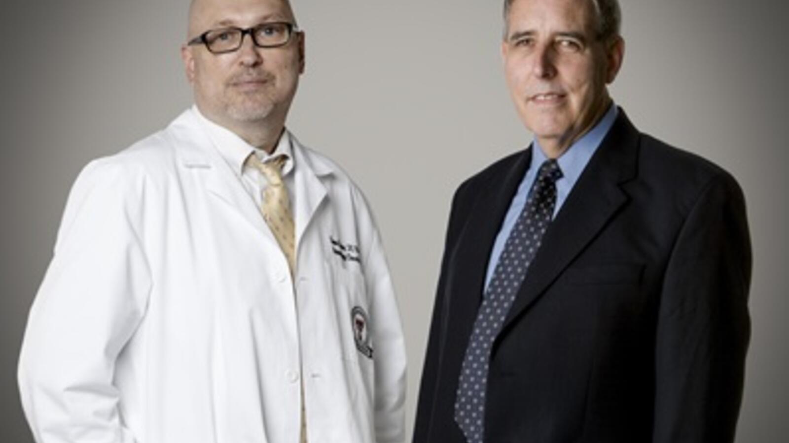 Huton and Reynolds stand in front of a studio backdrop