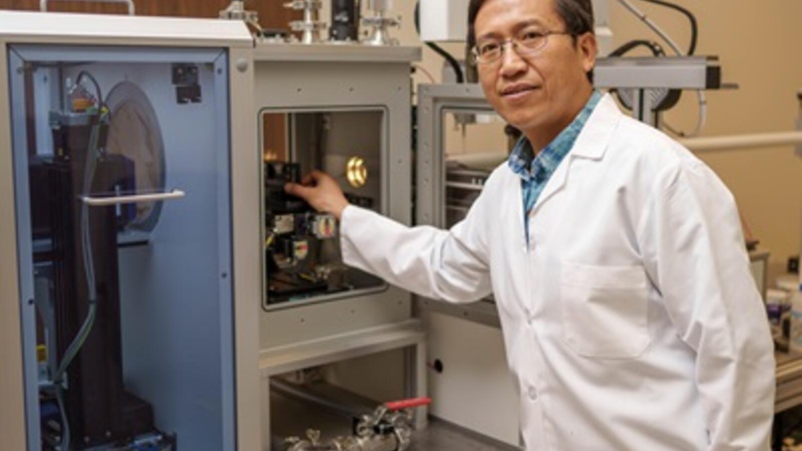 Hongjun “Henry” Liang, Ph.D. touching laboratory equipment