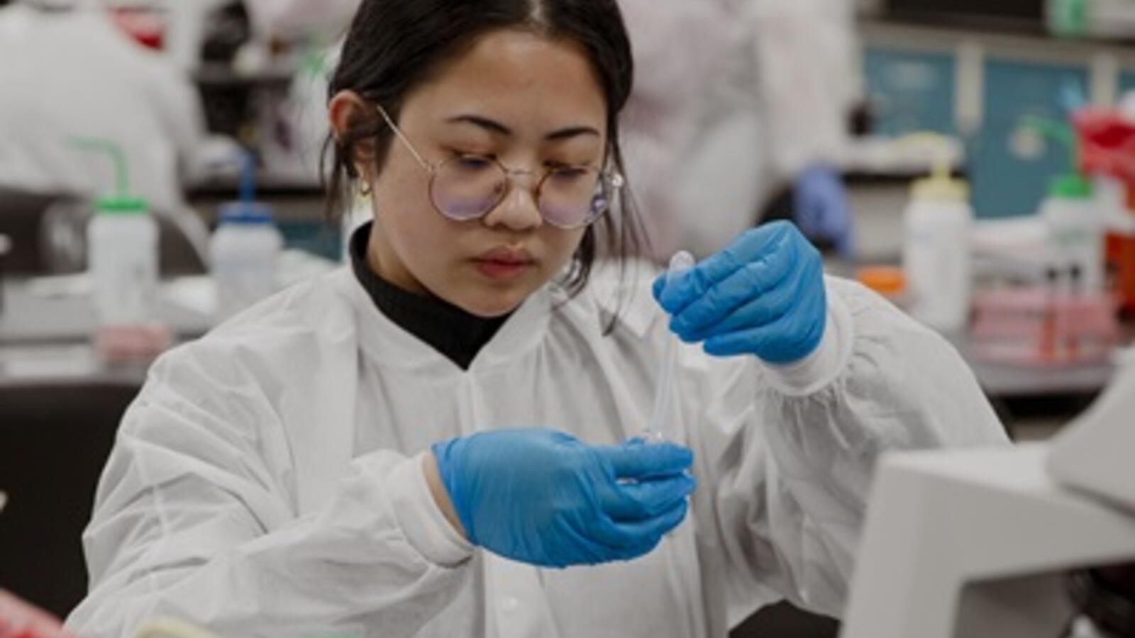 woman in a lab setting handling a vile