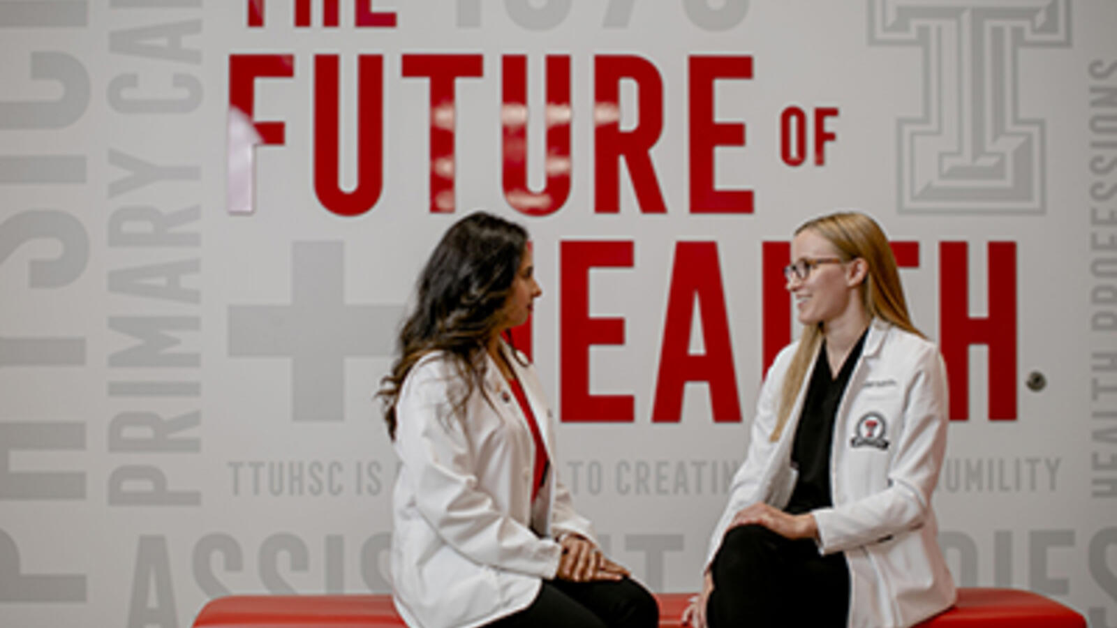 two health care professionals sitting on a bench, talking to each other