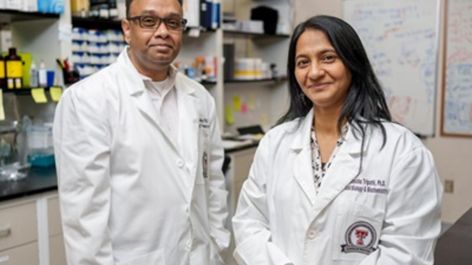two scientists smile wearing white coats