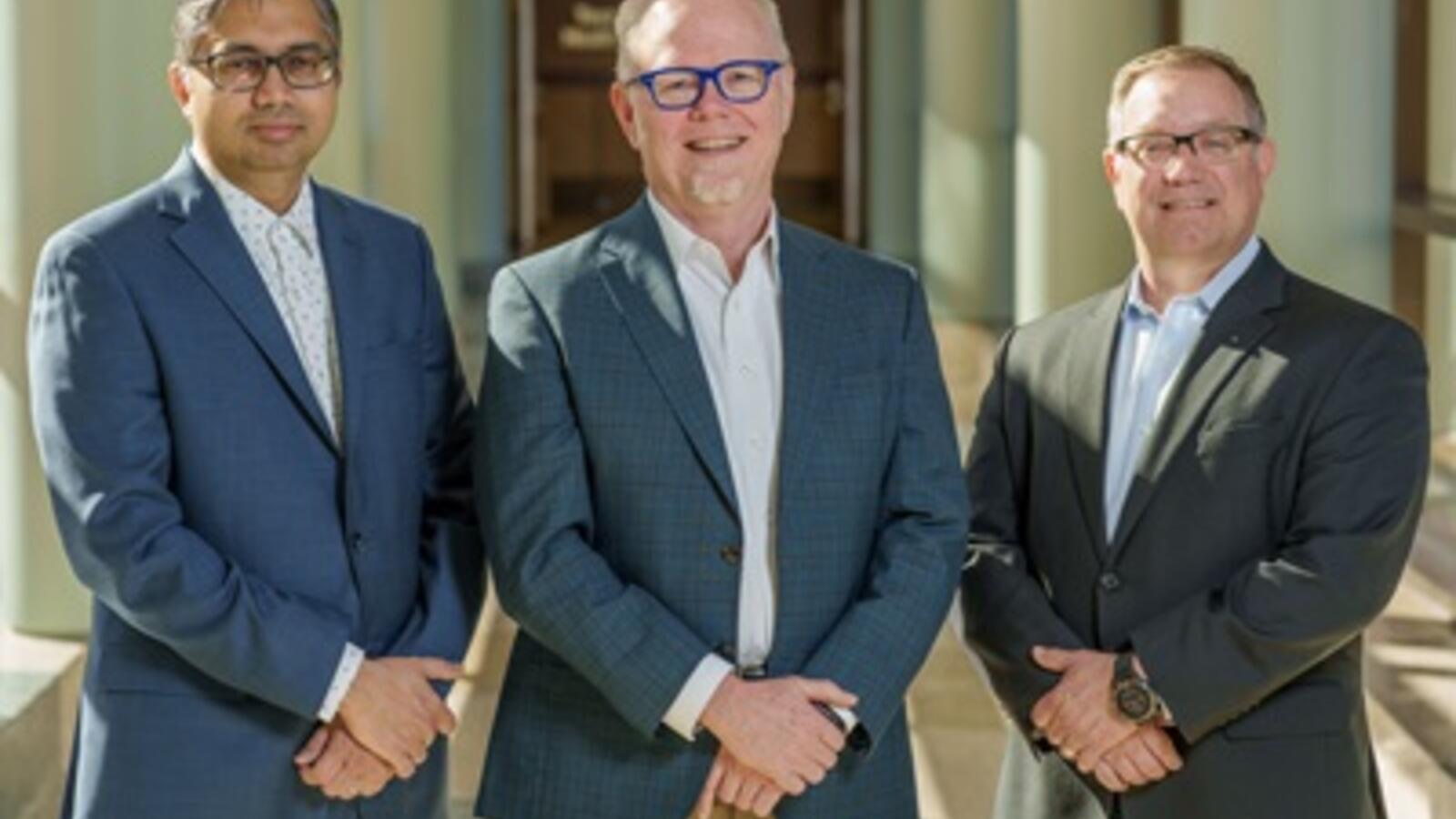 three men smiling, standing in a hallway at TTUHSC