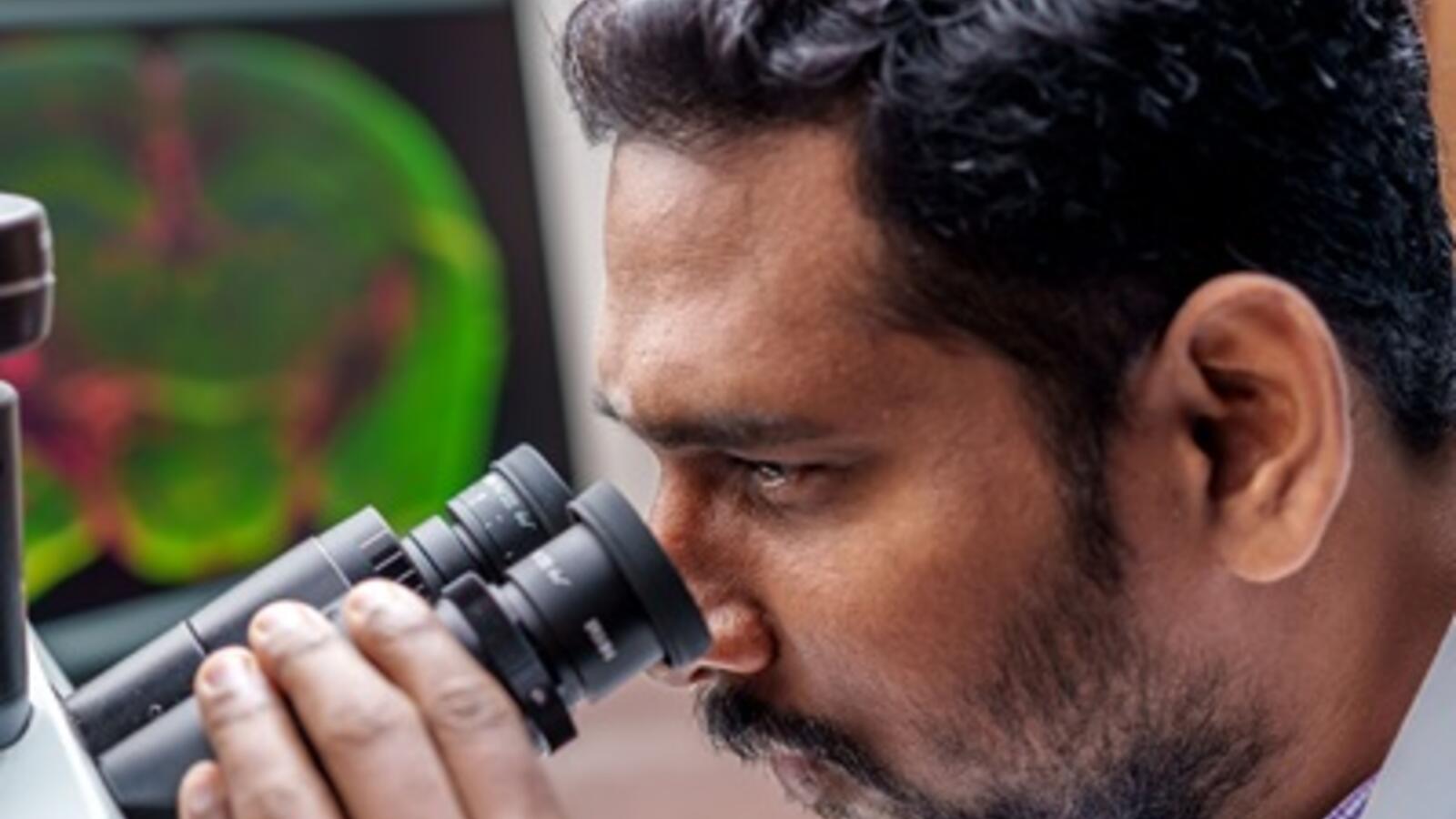Scientist looking through a microscope in a lab