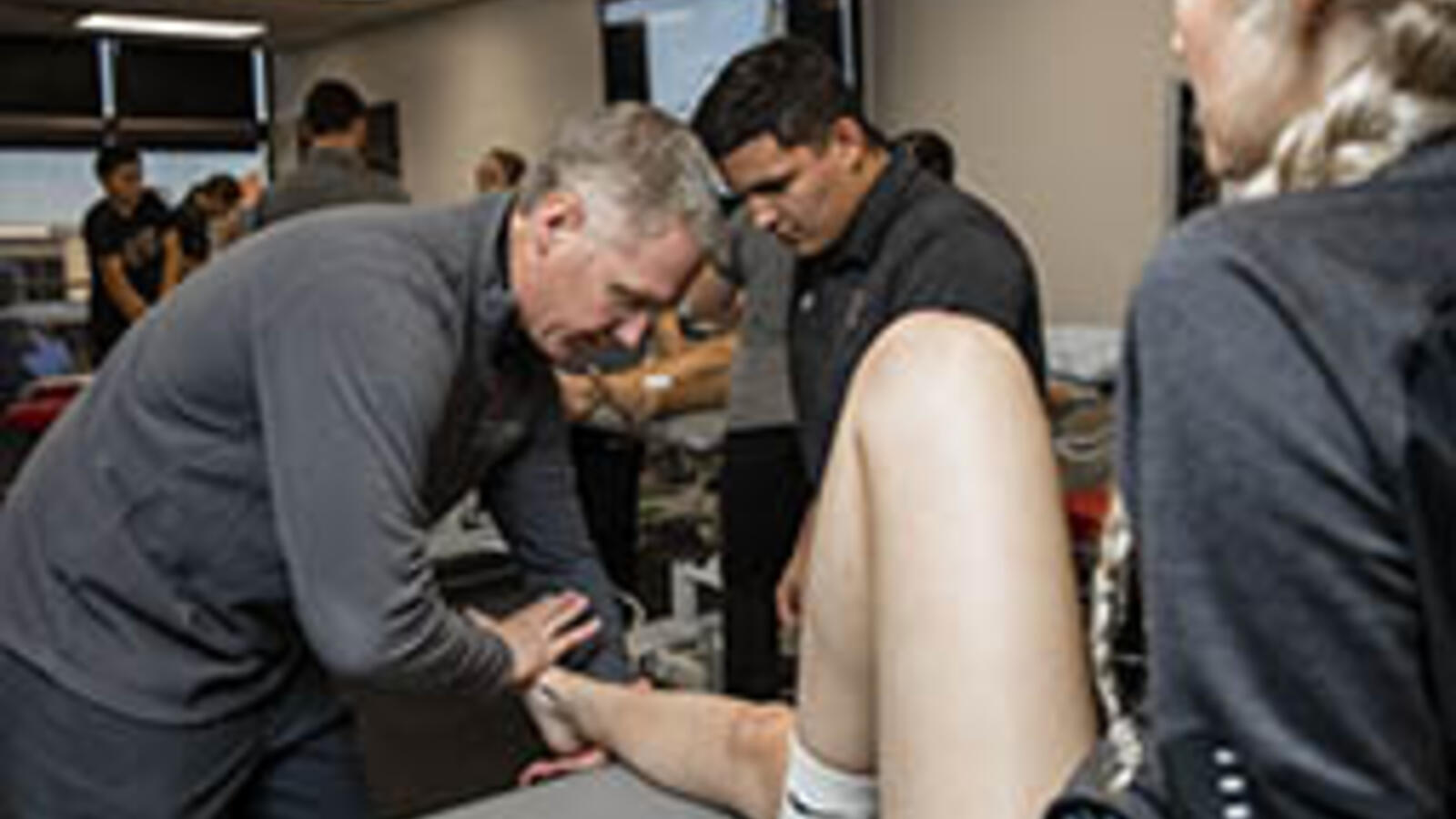 athletic trainer looking at an athlete's leg