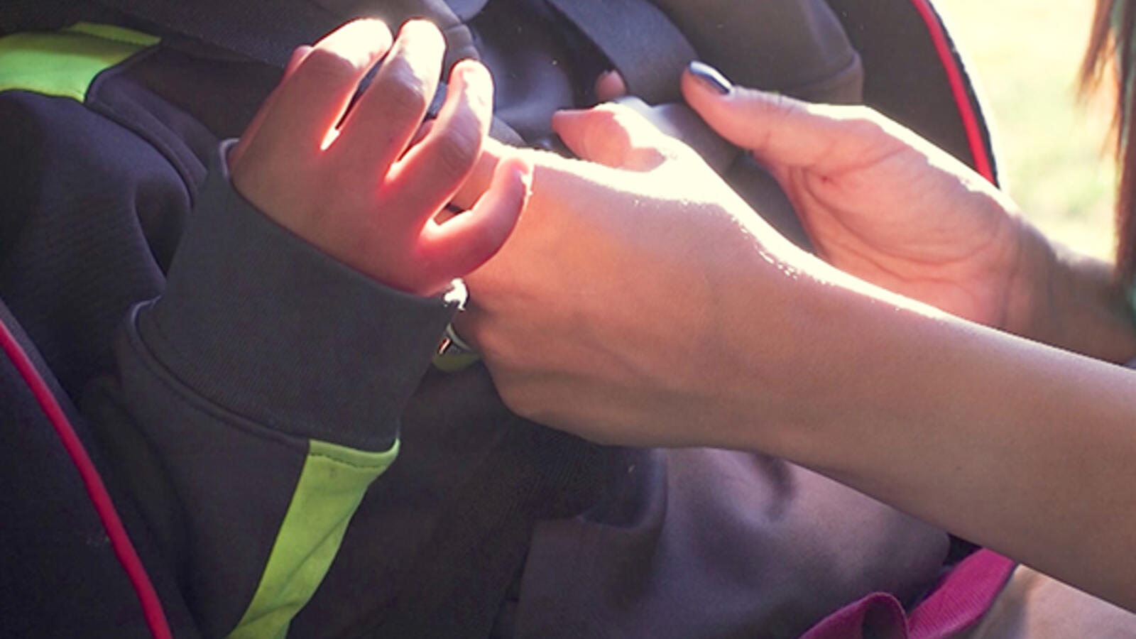 hands fastening a child into a car seat