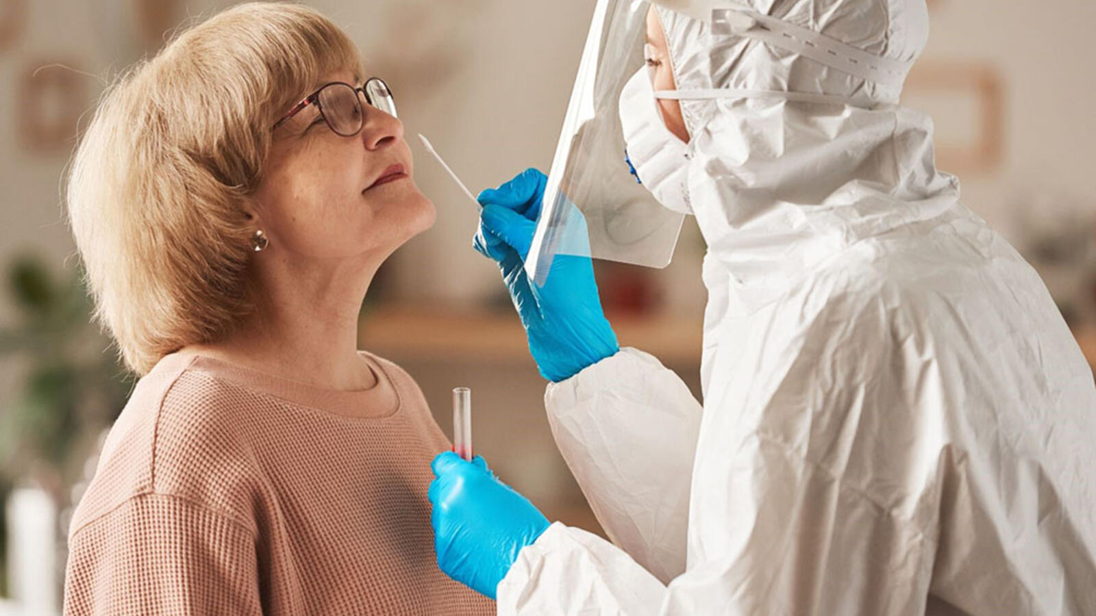 woman recieving a COVID-19 test from a health care professional in lab gear