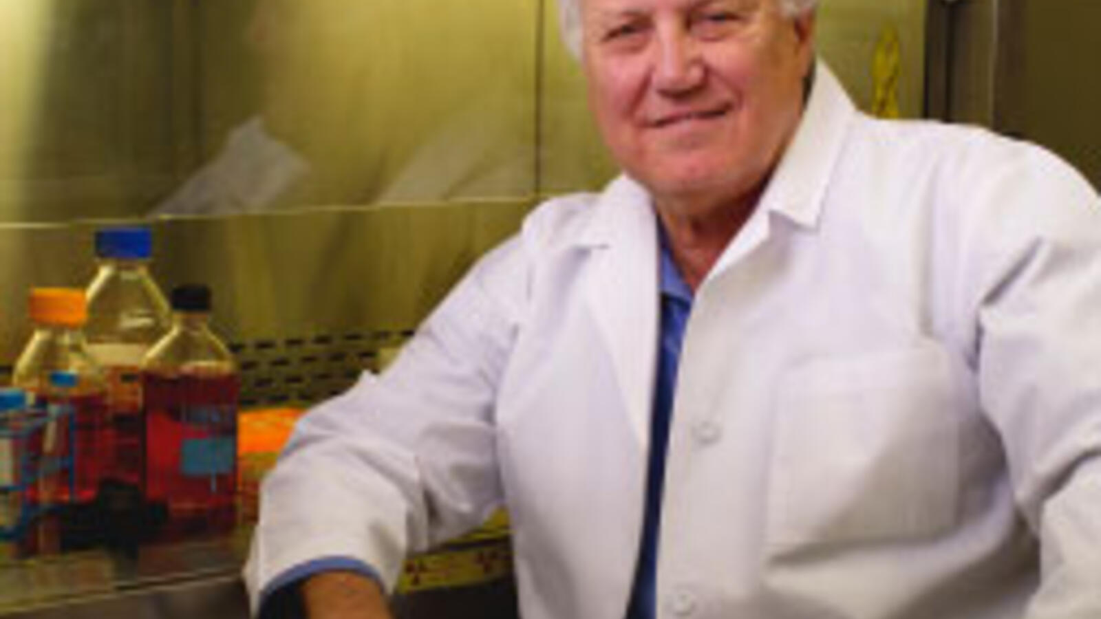 Male TTUHSC researcher wears a white coat and sits in his lab.