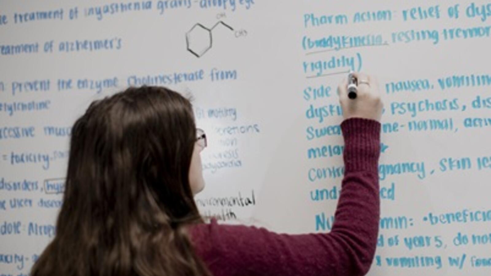 woman writing on a dry-erase board