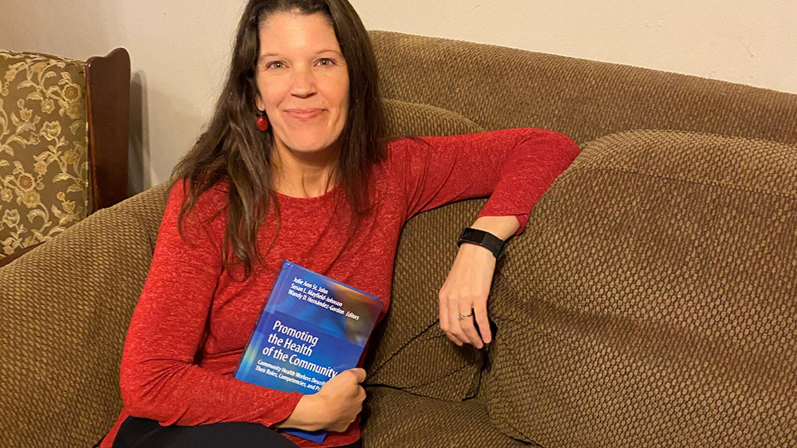 Julie St. John sitting with her textbook, recently published, covering Community health Workers or CHWs