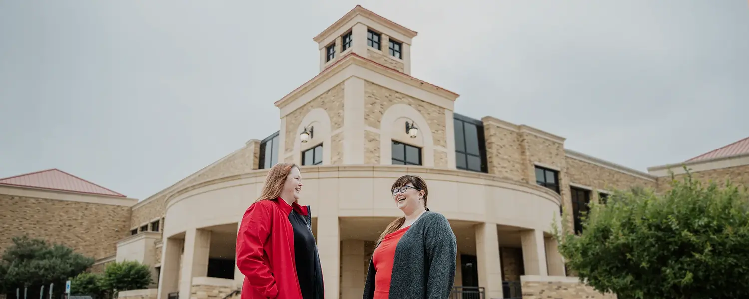 Two people standing outside a university health sciences building