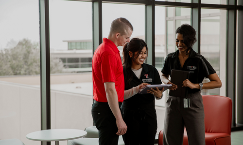 Three students together looking at a tablet.