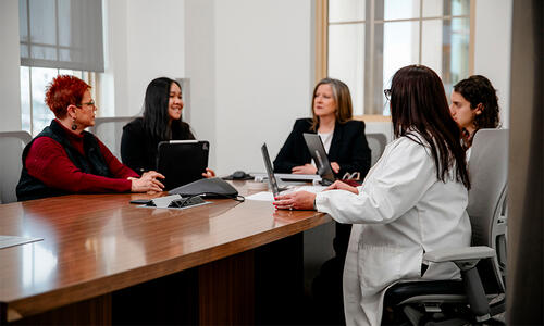 Five team members gathered around a conference table in a meeting room.