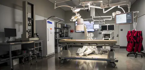 Medical research lab equipped with clinical training equipment and workstation monitors.