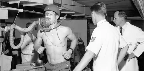Historic photo of a man undergoing a treadmill fitness test while medical researchers monitor him.