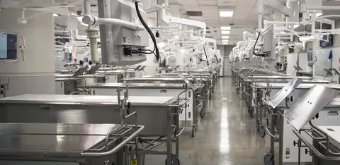 Medical dissection laboratory equipped with stainless steel examination tables and overhead lights.