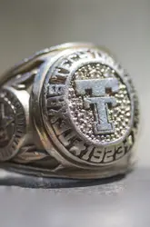 Close-up of a silver Texas Tech class ring displaying the iconic Double T emblem surrounded by textured detail and engraved lettering.